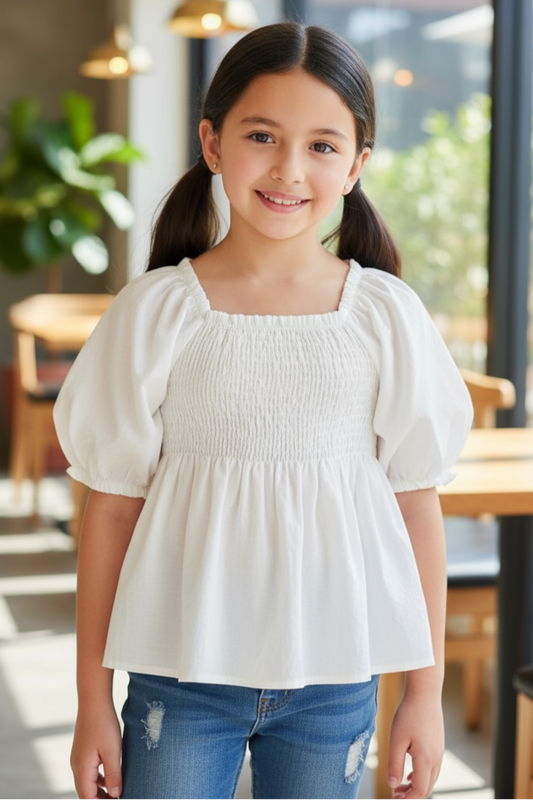 Young girl wearing a white blouse and blue jeans standing in a modern indoor setting.