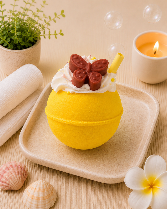Yellow bath bomb with a butterfly decoration on a wooden surface with bubbles and a candle.